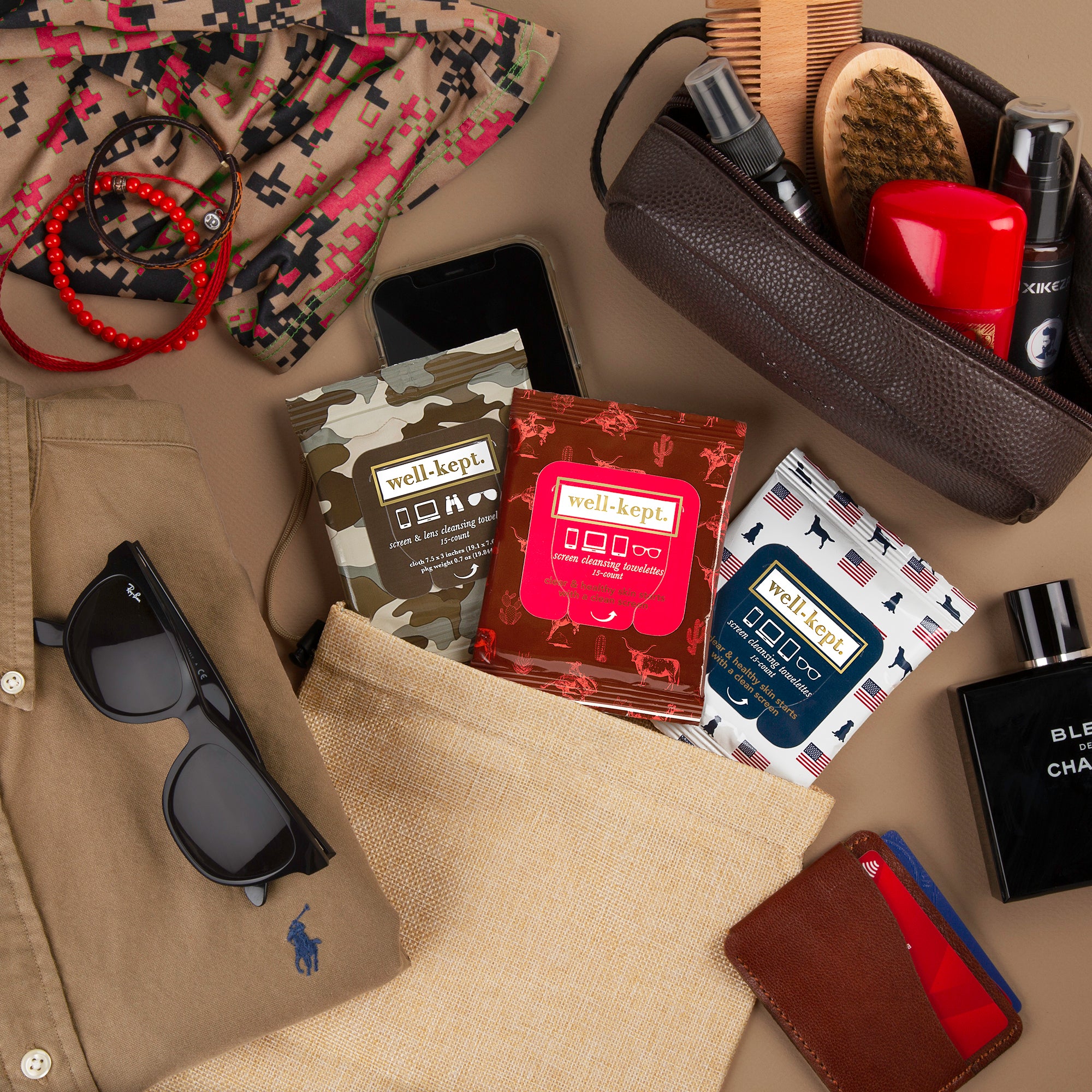 Flat lay of men's accessories featuring the TEXAS HOLD, 'EM - TWELVE PACK (12) electronics cleaning wipes, shirt, sunglasses, wallet, phone, and grooming items.
