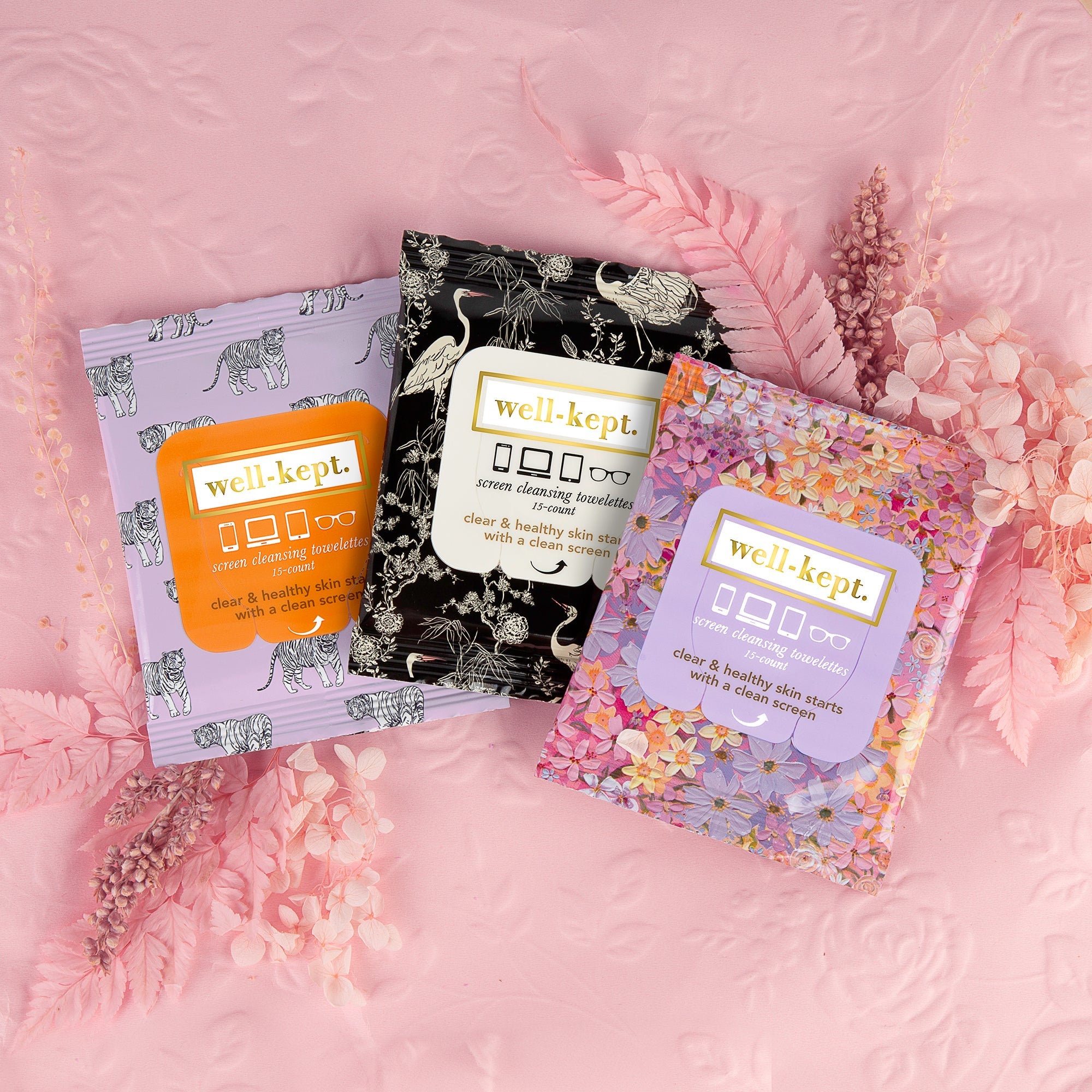 Three TIGER POSE - (24) Twenty Four Pack screen cleansing towelette packs sit on a pink floral background, making them the perfect wipes for keeping your electronics spotless.