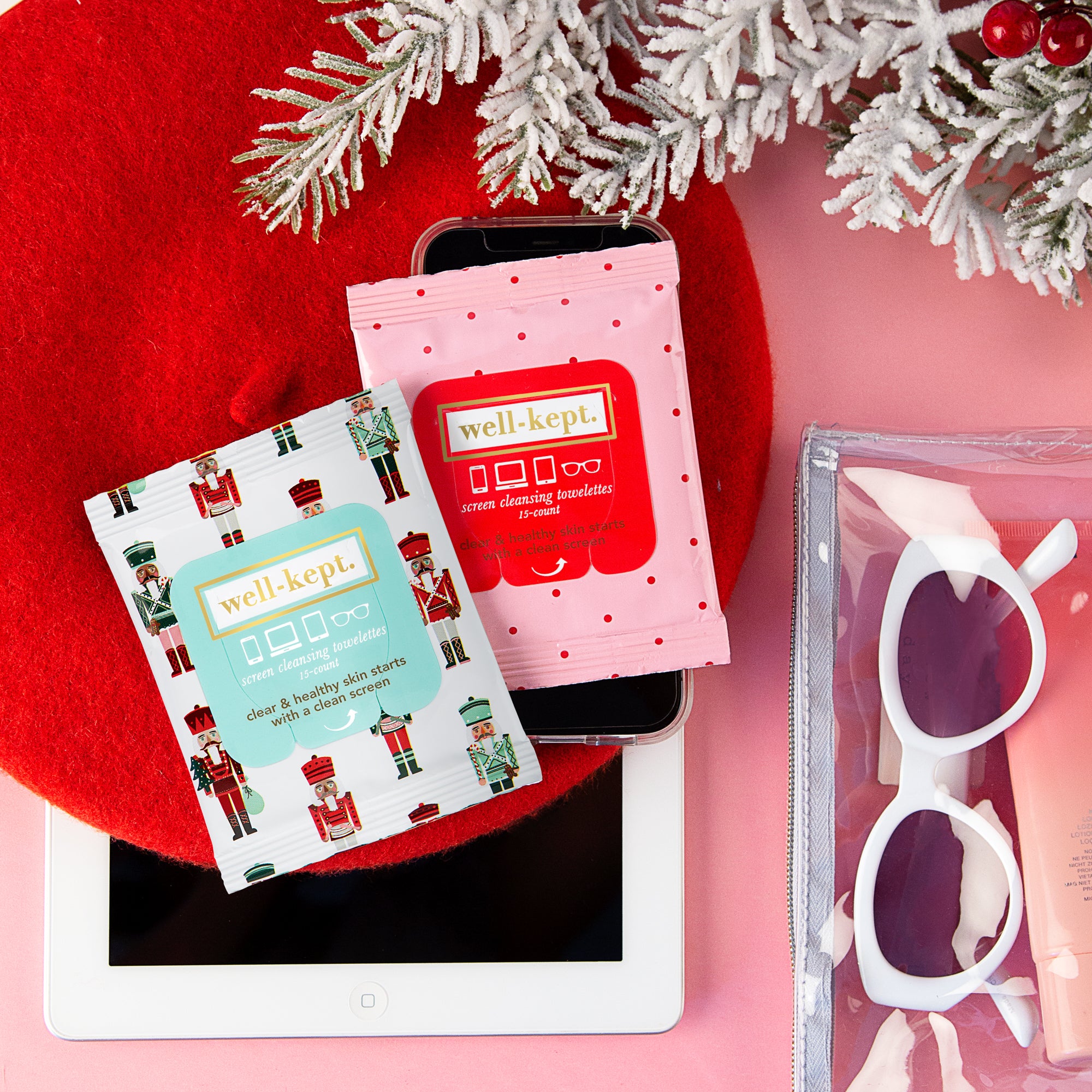A twelve-pack of NUTCRACKER electronics cleaning wipes sits on a tablet with sunglasses beneath a festive holiday decoration.