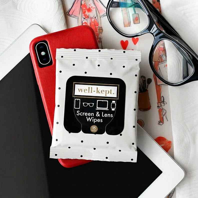 Jackie polka dot print Well-Kept screen and lens wipes pack styled with a red phone case, glasses, and a fashion sketch notebook
