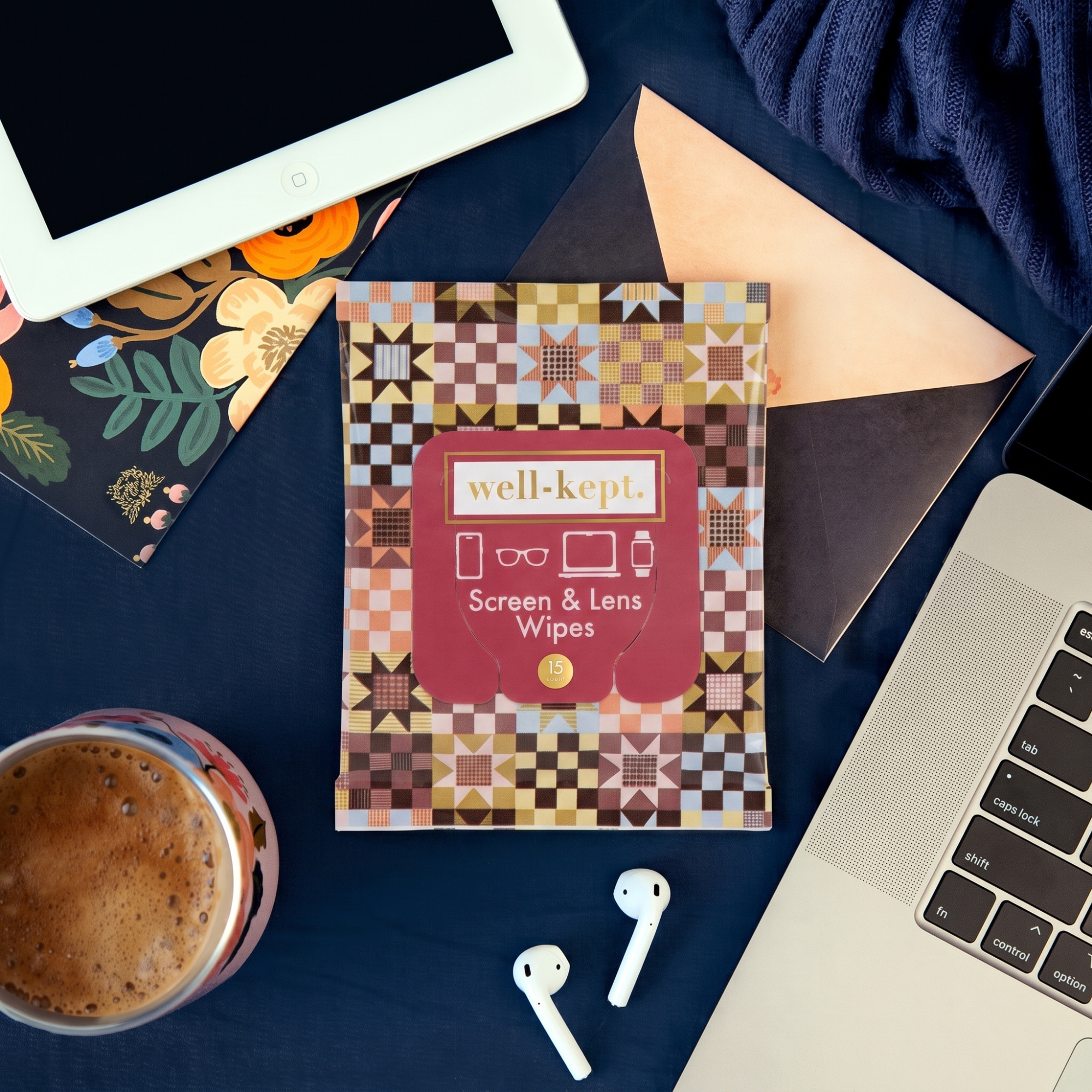 Storyteller Well-Kept screen and lens wipes pack on a desk with a laptop, iPad, AirPods, and a mug of coffee